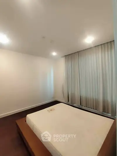 Spacious bedroom with large window and modern lighting in a contemporary apartment.