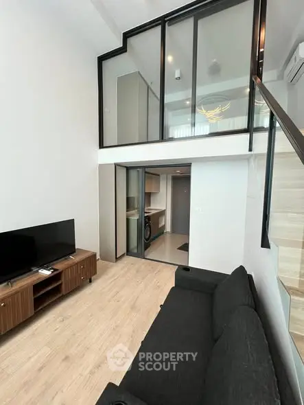 Modern loft apartment with mezzanine, sleek black-framed windows, and stylish wooden flooring.
