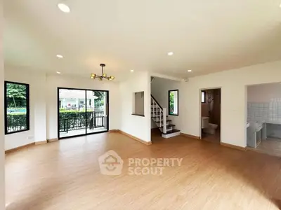 Spacious open-plan living room with modern lighting and large windows in a stylish home.
