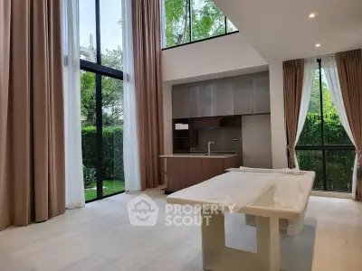 Spacious modern living room with high ceilings and large windows overlooking lush greenery.