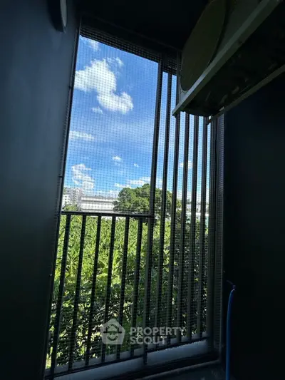 Scenic view from a modern balcony with lush greenery and blue sky.