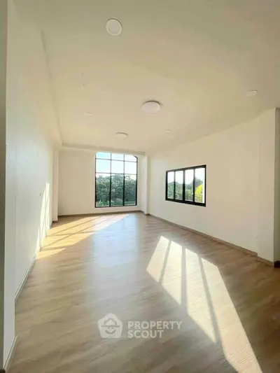 Spacious sunlit room with large windows and wooden flooring, perfect for modern living.