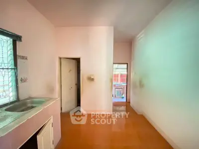 Cozy kitchen space with sink and tiled floor, featuring natural light from window.