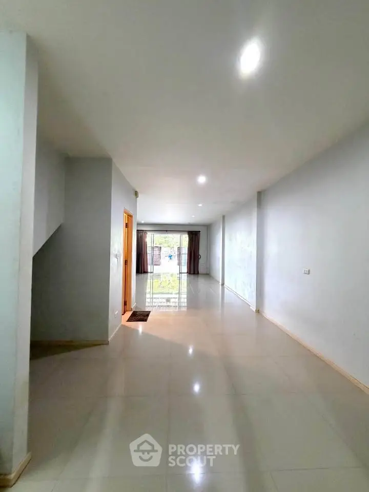 Spacious living room with large windows and glossy tiled floors, perfect for natural light and modern living.
