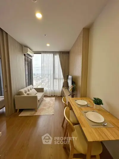 Modern living room with dining area, featuring wooden flooring and large window with city view.