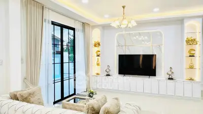 Luxurious living room with elegant decor and large TV, featuring plush seating and modern lighting.