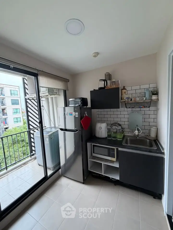 Modern compact kitchen with balcony view, featuring sleek appliances and stylish cabinetry.