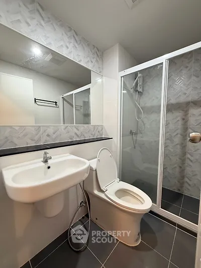 Modern bathroom with sleek design, featuring a shower enclosure and stylish sink.