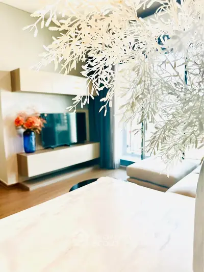 Modern living room with stylish decor and large TV, featuring elegant floral arrangement.