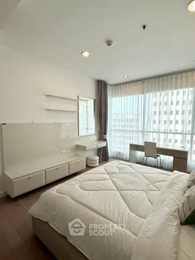 Bright and spacious bedroom with large windows and modern furnishings in a high-rise apartment.