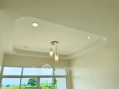 Modern ceiling design with recessed lighting and pendant lights in a bright room with large windows.