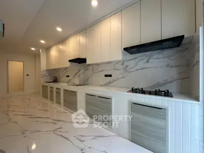 Luxurious modern kitchen with marble flooring and sleek cabinetry, featuring a gas stove and ample storage space.