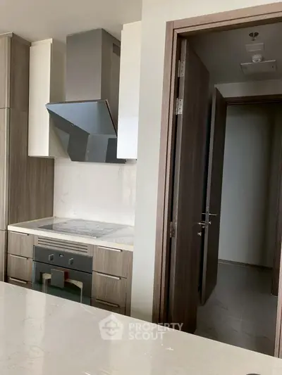 Modern kitchen with sleek cabinetry and built-in oven, featuring a minimalist design.