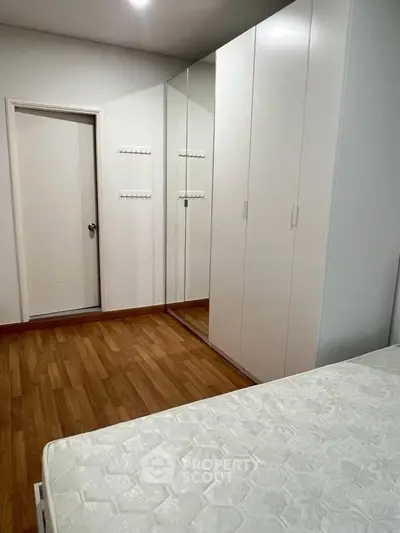 Spacious bedroom with wooden flooring and large wardrobe in modern apartment