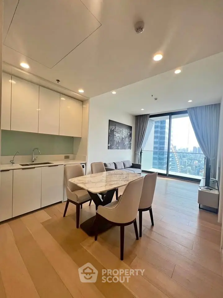 Modern open-plan living room with kitchen, dining area, and city view balcony in luxury apartment.