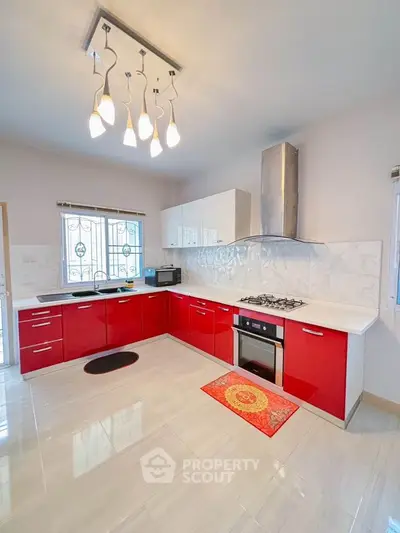 Modern kitchen with red cabinets, gas stove, and sleek lighting