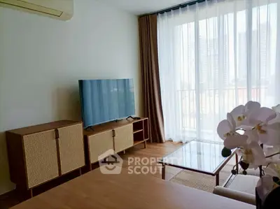 Modern living room with large TV, wooden furniture, and city view through sheer curtains.