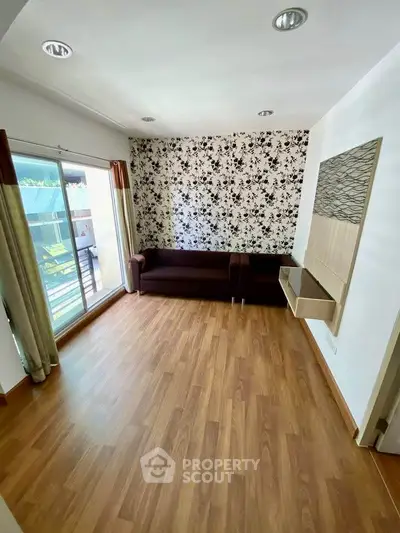 Spacious living room with wooden flooring and balcony access in modern apartment.