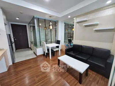 Modern living room with open dining area, featuring sleek furniture and wooden flooring.