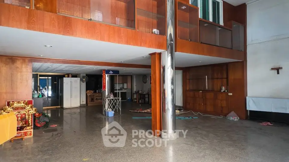 Spacious open-plan living area with modern design and high ceilings, featuring polished floors and wooden accents.