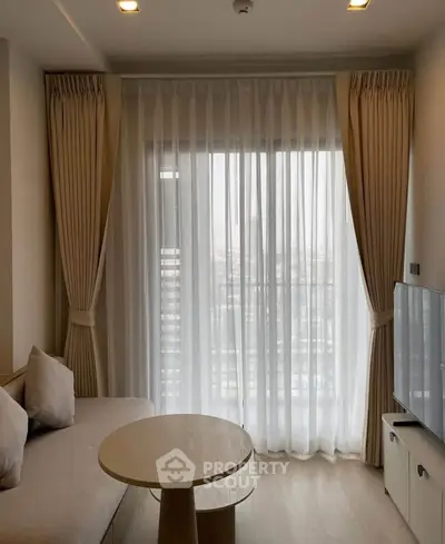 Modern living room with floor-to-ceiling windows and elegant curtains, featuring a cozy sofa and sleek TV setup.