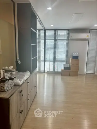 Spacious room with wooden flooring and large windows, ideal for office or living space.