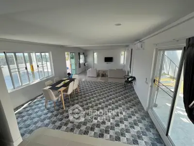 Spacious open-plan living and dining area with modern decor and large windows.