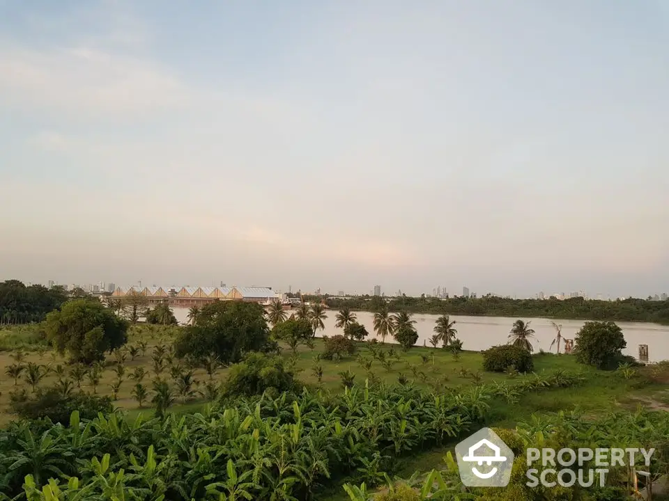 Scenic river view with lush greenery and distant city skyline, perfect for tranquil living.