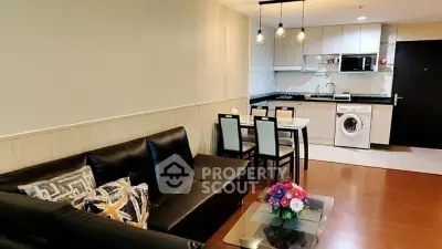 Modern open-layout living room with kitchen, featuring sleek furniture and stylish lighting.
