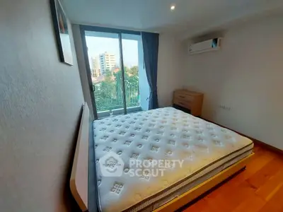 Spacious bedroom with large window and city view, featuring modern air conditioning and wooden flooring.