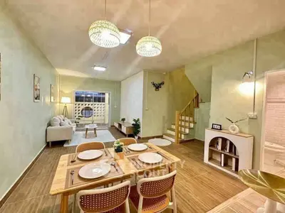 Charming open-plan living and dining area with modern decor and staircase, perfect for cozy gatherings.