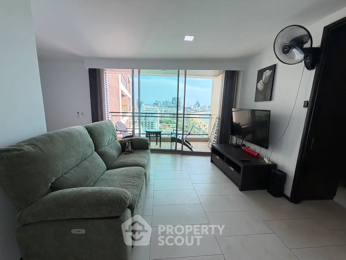 Spacious living room with city view and balcony access, featuring modern furniture and entertainment setup.
