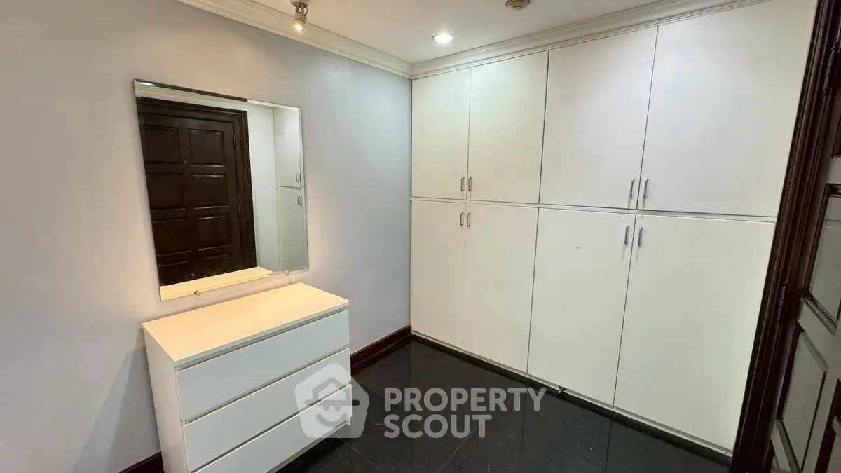 Spacious storage room with sleek white cabinets and modern dresser in a well-lit interior.