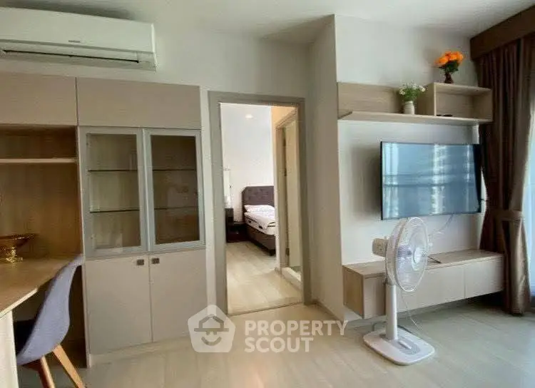 Modern living room with sleek furniture and wall-mounted TV, leading to a cozy bedroom.