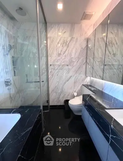 Luxurious marble bathroom with sleek black countertops and modern fixtures.