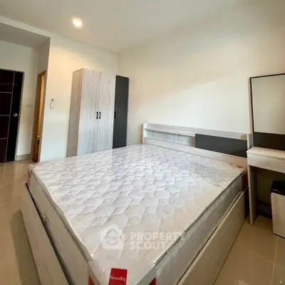 Spacious bedroom with modern furniture and large bed in a well-lit apartment.