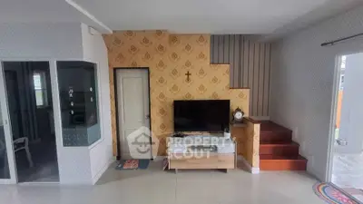 Charming living room with stylish wallpaper, modern TV setup, and elegant staircase in cozy home.