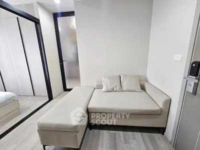 Modern living room with beige sectional sofa and sliding glass door leading to bedroom.
