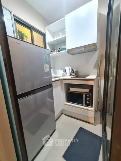 Compact modern kitchen with stainless steel fridge and microwave, ideal for urban living.