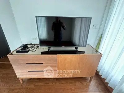 Modern living room with sleek wooden TV stand and flat-screen TV, showcasing contemporary interior design.