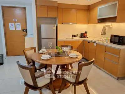 Modern kitchen with wooden cabinets and dining area in cozy apartment.
