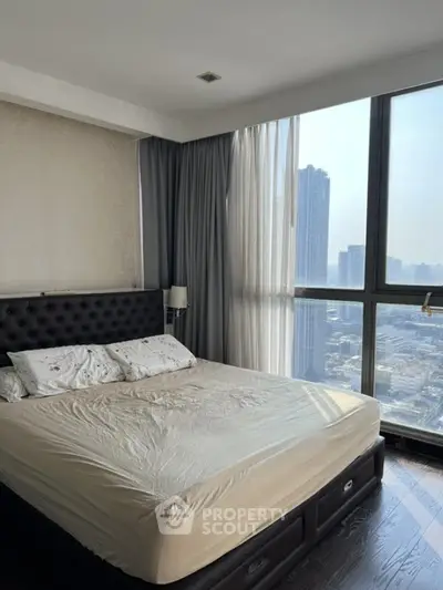 Spacious bedroom with large windows offering stunning city views