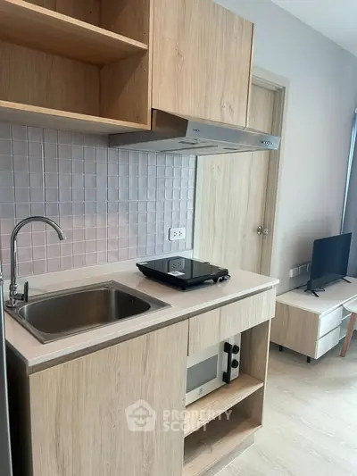 Modern compact kitchen with wooden cabinets and sleek appliances in a stylish apartment.