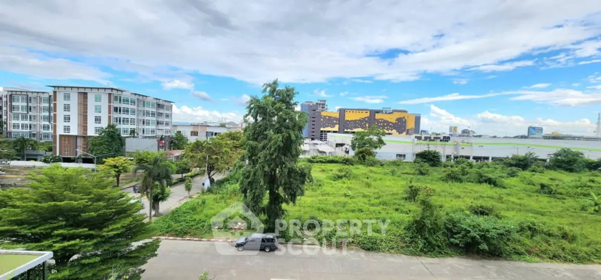 Scenic view of lush greenery and modern buildings under a vibrant blue sky.