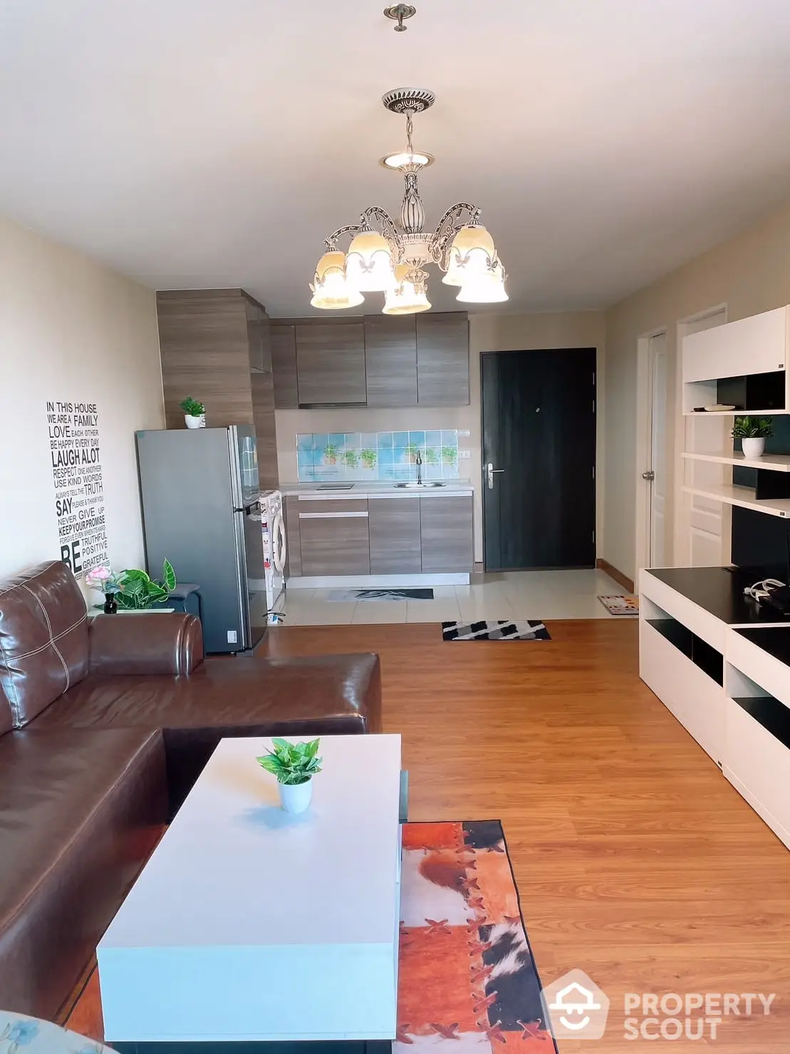 Spacious living room seamlessly connects to a modern kitchen, featuring elegant lighting, sleek cabinetry, and hardwood floors, ideal for entertaining and comfortable living.