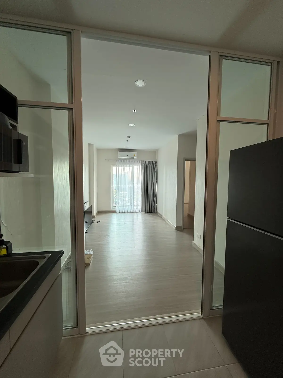 Modern open-layout kitchen leading to spacious living room with large windows
