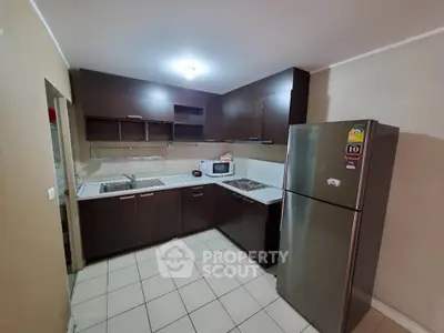 Modern kitchen with dark wood cabinets and stainless steel fridge