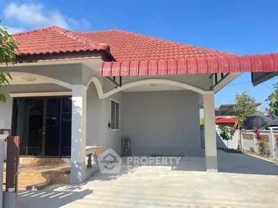 Charming single-story home with red-tiled roof and spacious driveway in a serene neighborhood.
