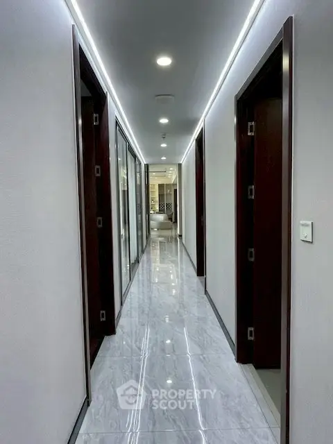 Sleek modern corridor with glossy marble flooring and recessed lighting in upscale building.