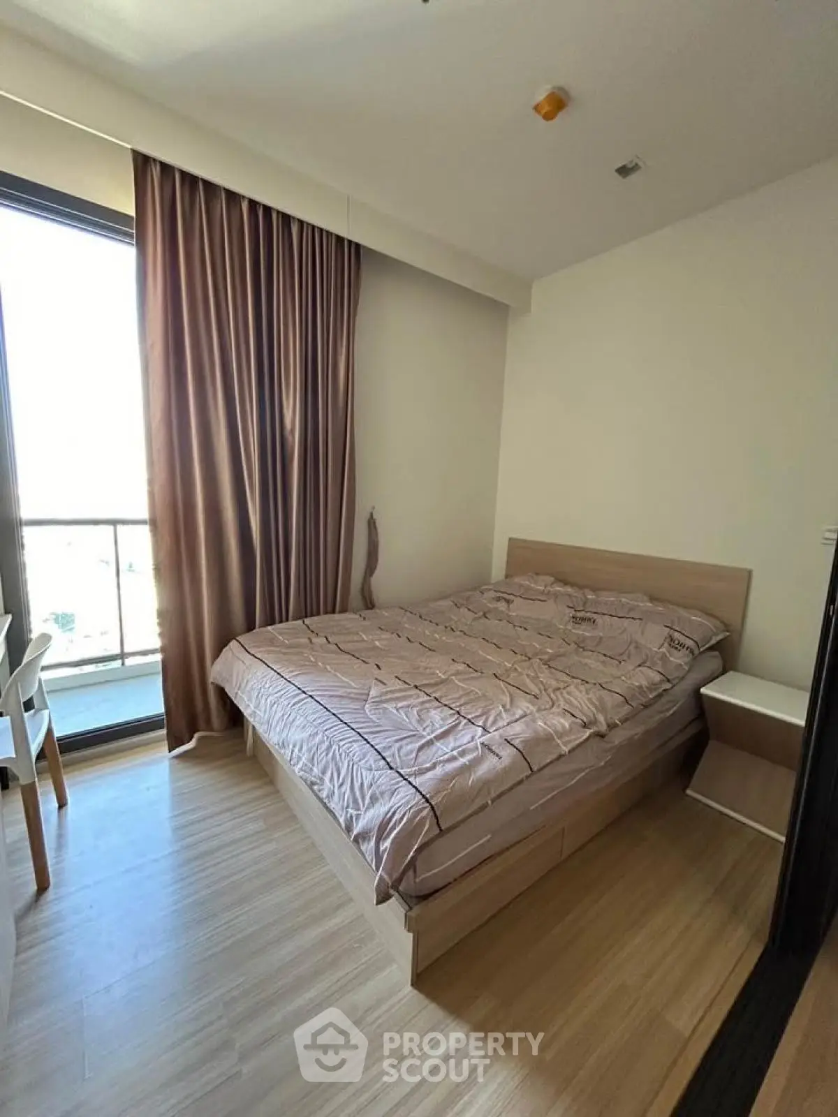 Cozy bedroom with wooden flooring and large window for natural light